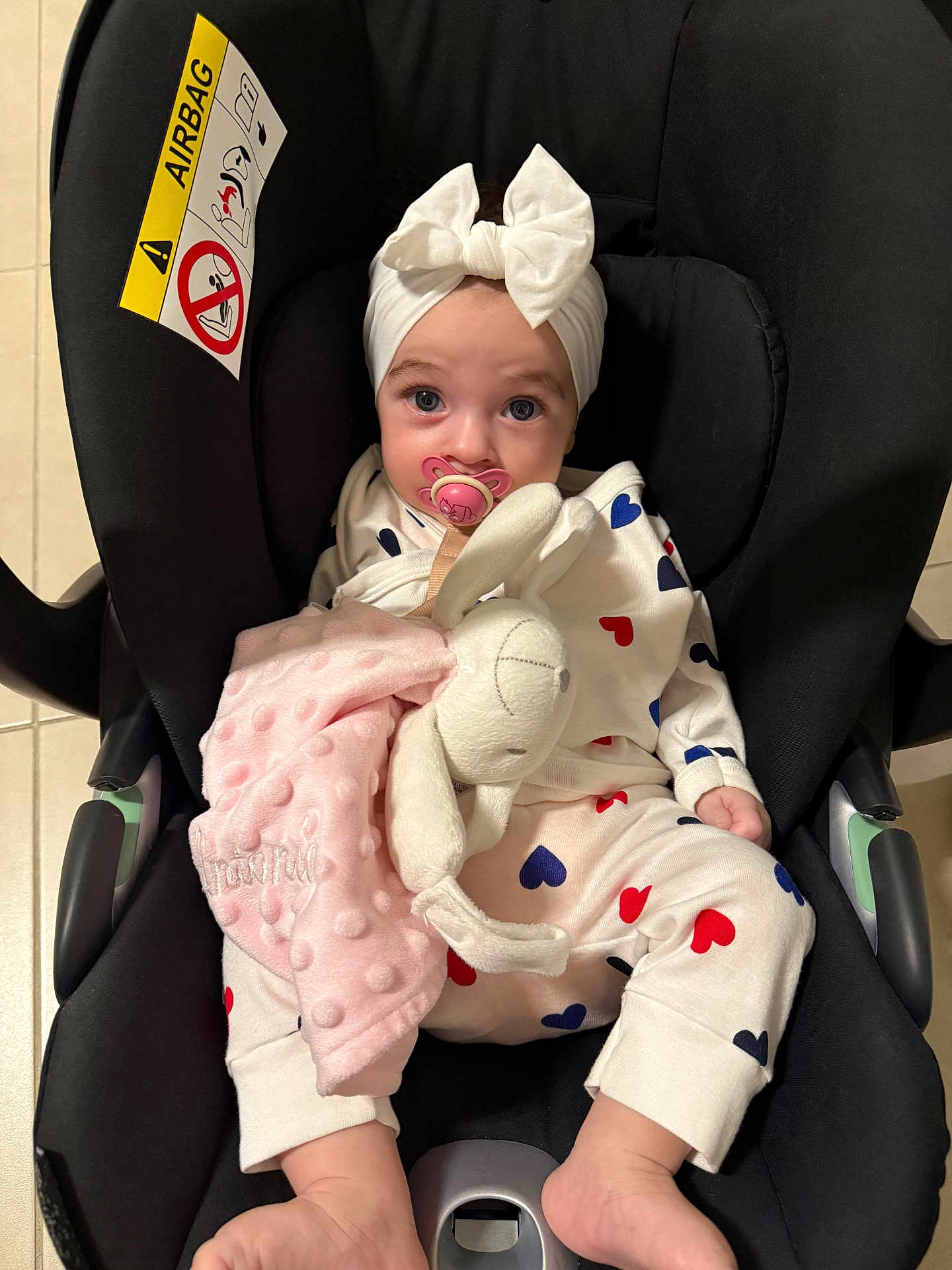 Antonia participe au concours pour gagner de l'argent avec cette photo : baby, car_seat, pacifier, headband, bow, plush_toy, bunny, pajamas, hearts, infant, child, cute, indoors, soft_toy, comfort, seat, foot, face, clothing, pink