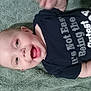 baby, smiling, infant, towel, clothing, text, blue_shirt, happy, face, mouth_open, eyes, skin, head, arm, lying_down, indoors, person, cute, expression, cheerful