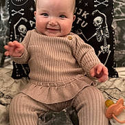 Frances joined the competition — help win amazing prizes! baby, child, smiling, ribbed_clothing, beige_outfit, blanket, pacifier, pillow, skeleton_design, celestial_symbols, indoor, portrait, happy, seated, cute, infant, face, hand, cozy, soft_fabric