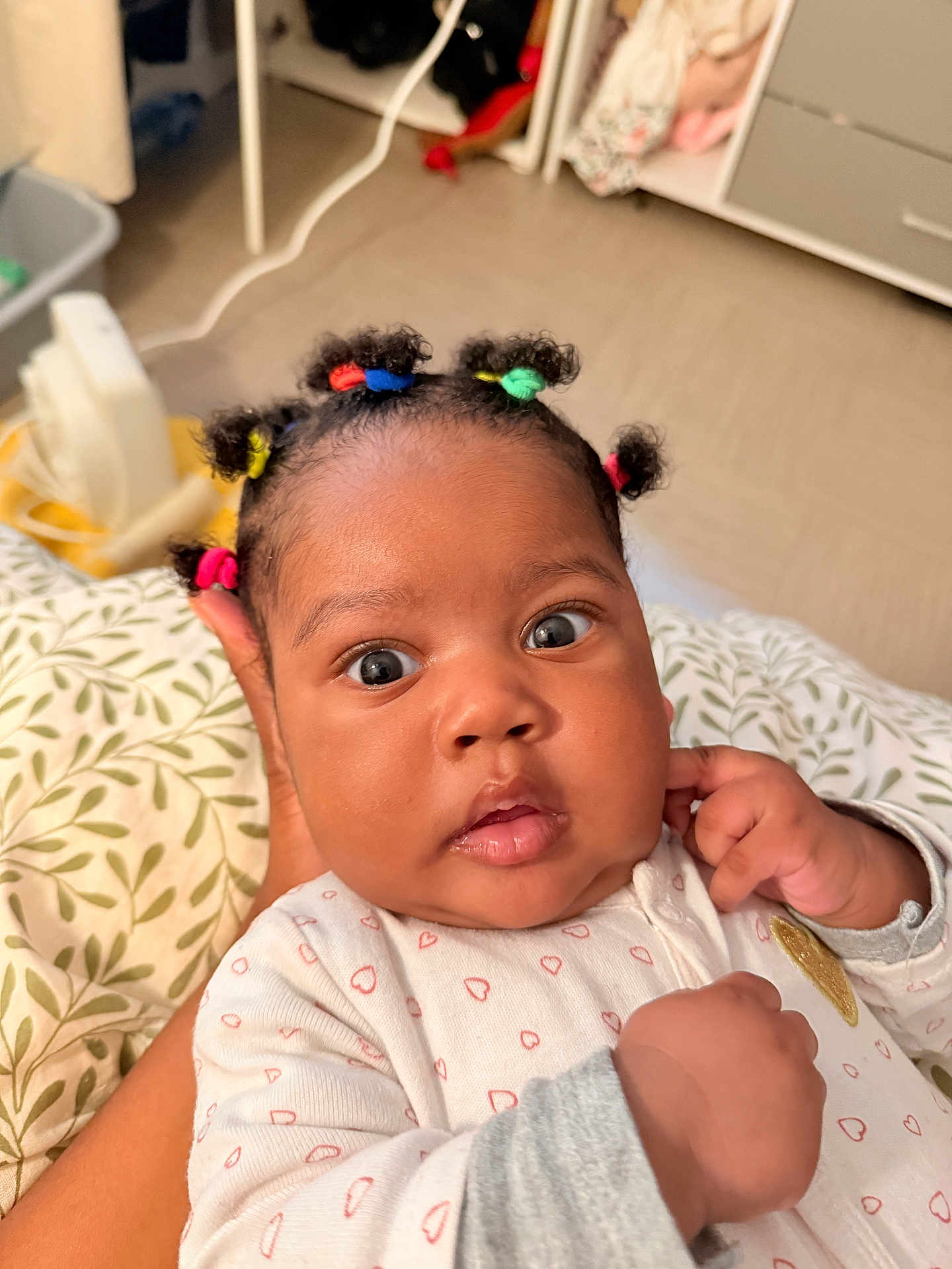 Keyanna participe au concours pour gagner de l'argent avec cette photo : baby, child, infant, face, hair_ties, onesie, hand, cushion, pattern, indoor, person, expression, wide_eyes, skin, curly_hair, clothing, support, close_up, human, portrait