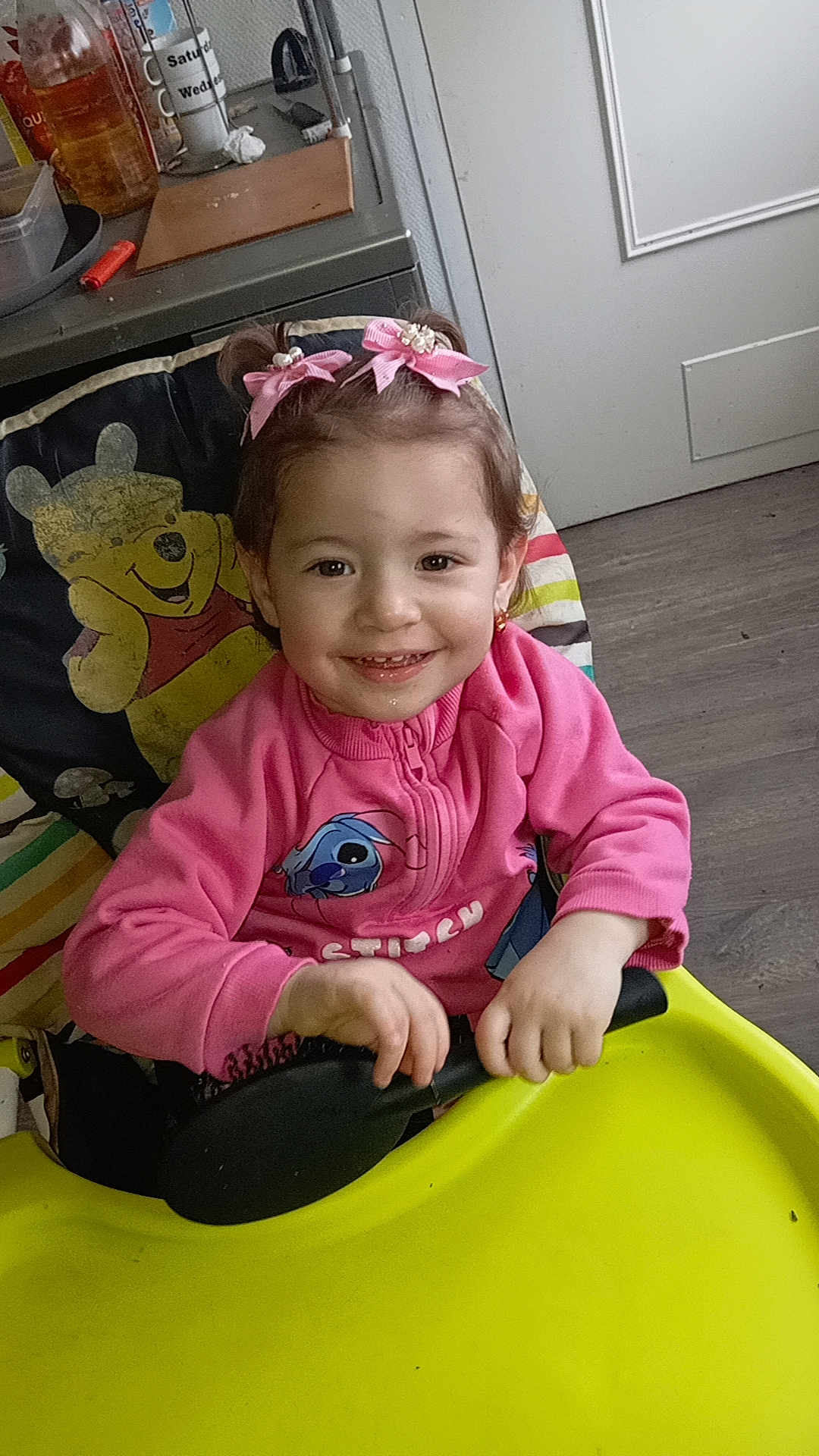 Klensy a rejoint le concours — aidez-le/la à gagner de superbes lots ! toddler, child, smiling, pink_jacket, hair_bows, high_chair, winnie_the_pooh, hairbrush, indoor, kitchen, floor, door, table, plastic_tray, furniture, person, cute, happy, young_child, playful