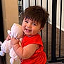 Ethan is registered to the contest to win money with this photo: baby, baby_gate, carpet, child, chubby_cheeks, cute, furniture, happy, home, indoor, jeans, person, plush_toy, red_shirt, short_hair, smiling, standing, tile_floor, toddler, toy