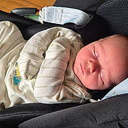 George is registered to the contest to win money with this photo: baby, car_seat, child, clothing, comfort, cute, face, head, indoor, infant, newborn, onesie, peaceful, portrait, resting, seatbelt, skin, sleeping, soft_light, toddler
