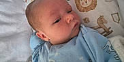 George is registered to the contest to win money with this photo: baby, infant, blanket, blue_onesie, crib, animal_print, giraffe, lion, sleepwear, cute, newborn, face, child, bed, soft, pattern, cozy, resting, indoors, peaceful