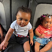 Gemariaa Gemarion joined the competition — help win amazing prizes! child, toddler, car_seat, baby, clothing, hair_clips, denim_skirt, white_shirt, black_shorts, socks, seatbelt, curly_hair, indoor, portrait, two_children, cute, looking_at_camera, infant, casual, car_interior