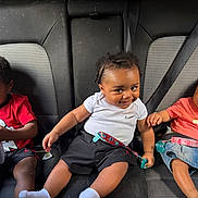 Gemarion joined the competition — help win amazing prizes! child, toddler, car_seat, seatbelt, smiling, curious, clothing, red_shirt, white_shirt, denim_skirt, hair_accessories, indoors, transportation, seat, cute, people, portrait, sitting, baby, friendship