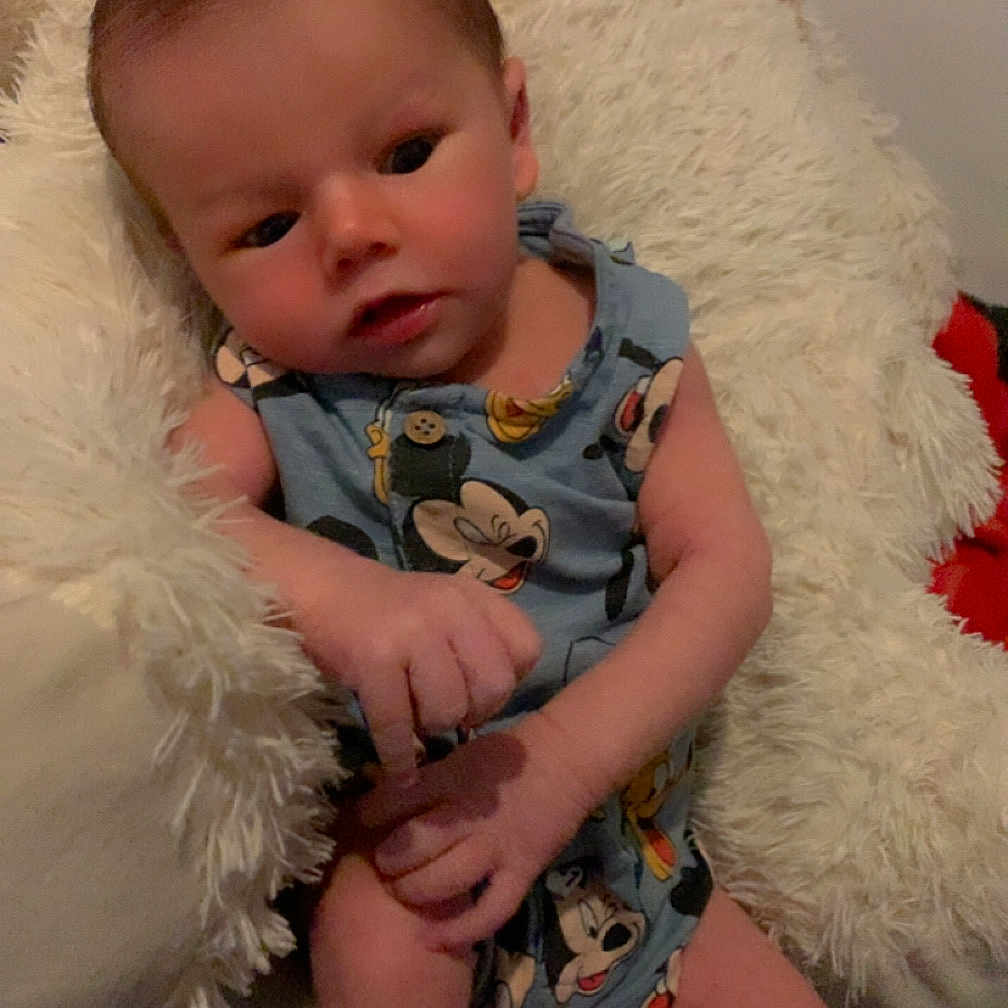 Aylan a rejoint le concours — aidez-le/la à gagner de superbes lots ! baby, blue_clothing, child, comfortable, couch, cute, expression, fluffy_pillow, hands, indoor, infant, legs, mickey_mouse, person, portrait, relaxed, seated, skin, soft_texture, young