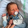 newborn, baby, pacifier, hand, blanket, clothing, mickey_mouse, infant, skin, face, bed, comfort, cute, sleepy, toddler, child, holding, soft, person, resting