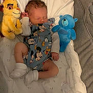 Aylan participe au concours pour gagner de l'argent avec cette photo : baby, newborn, sleeping, mickey_mouse, onesie, plush_toy, lion_toy, blue_bear, blanket, sock, infant, bed, resting, cute, soft, child, cozy, indoors, comfort, peaceful
