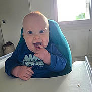 Tybaut participe au concours pour gagner de l'argent avec cette photo : baby, high_chair, indoor, blue_shirt, happy, smiling, child, face, fingers, mouth, window, light, cozy, cute, infant, person, expression, seated, playful, portrait