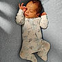 David is registered to the contest to win money with this photo: baby, newborn, sleeping, onesie, hot_air_balloon_pattern, blanket, blue, soft_texture, infant, peaceful, cute, clothing, portrait, hands_up, closed_eyes, indoors, resting, cozy, child, sleep