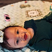 Eden is registered to the contest to win money with this photo: baby, smiling, face, infant, bow, hair, blanket, texture, green_clothing, ribbed_fabric, lying_down, happy, cute, child, portrait, indoor, soft_light, closeup, person, skin