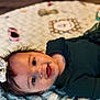 baby, smiling, face, infant, bow, hair, blanket, texture, green_clothing, ribbed_fabric, lying_down, happy, cute, child, portrait, indoor, soft_light, closeup, person, skin
