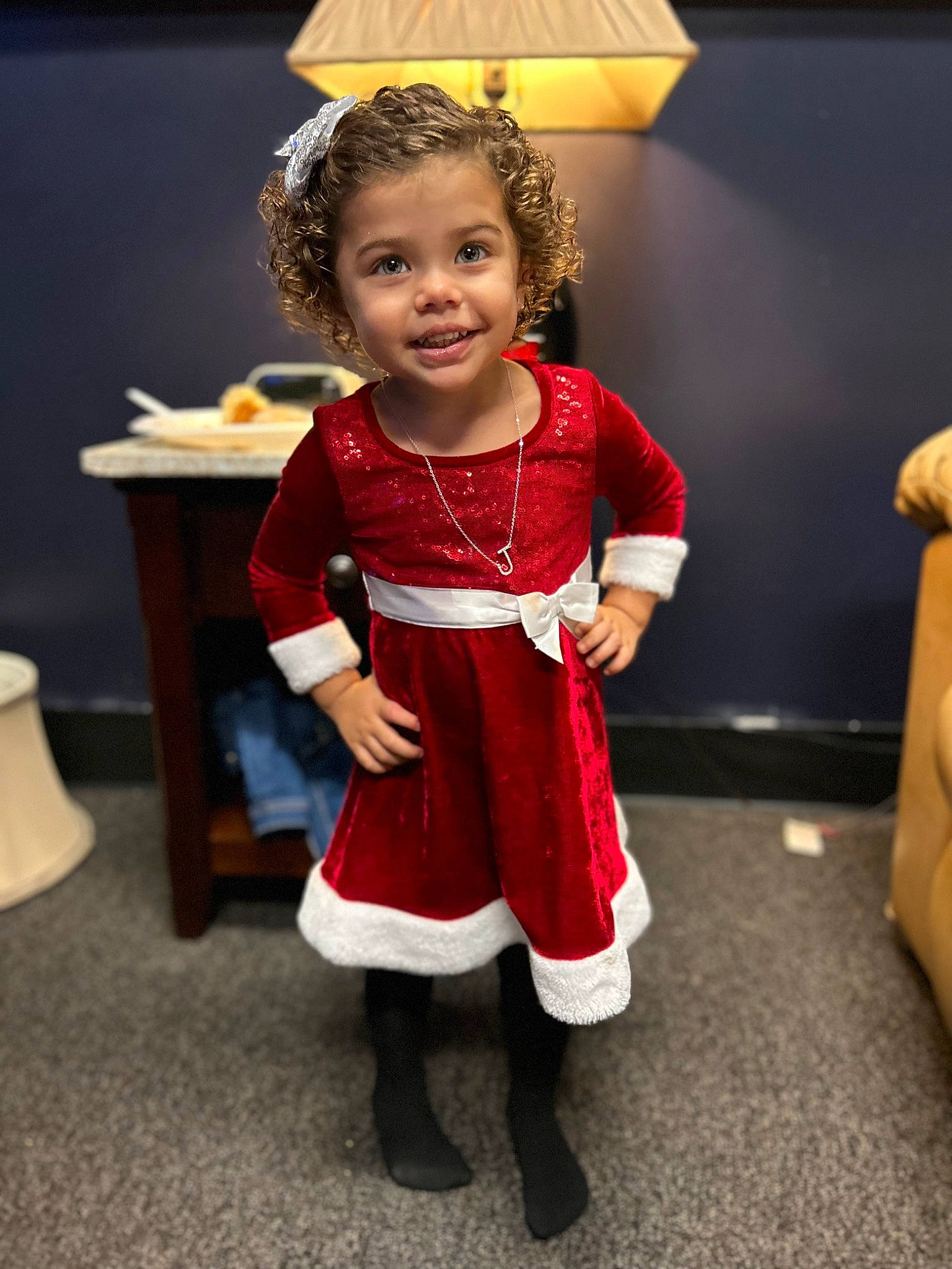 Jenevie is registered to the contest to win money with this photo: boot, chair, child, costume, event, face, fashion_design, flooring, fun, happy, human_leg, joy, knee, lamp, person, room, sitting, smile, sock, toddler