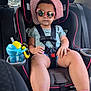 toddler, child, car_seat, car, seatbelt, hat, sunglasses, pink, blue_shirt, shorts, shoes, sippy_cup, toy, sitting, backseat, window, daylight, casual, cute, serious