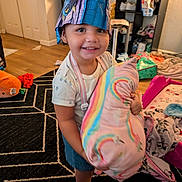 Aria joined the competition — help win amazing prizes! toddler, child, smiling, indoor, hat, pillow, rainbow, toy, rug, floor, furniture, blanket, clothing, socks, playroom, happy, face, person, home, cute