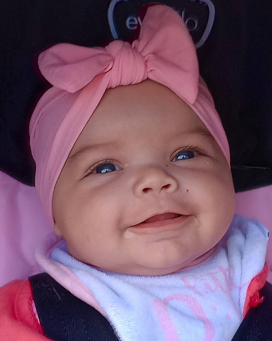Keira is registered to the contest to win money with this photo: baby, cap, cheek, chin, eye, eyebrow, eyelash, facial_expression, happy, headgear, headwear, iris, joy, lip, nose, person, pink, purple, skin, smile