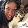 person, cat, tabby_cat, white_cat, pet, cuddling, smiling, portrait, selfie, face, whiskers, ears, eyes, fur, blanket, couch, indoors, cozy, companion, relaxed