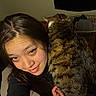 woman, cat, tabby_cat, pet, selfie, portrait, cuddling, indoors, bedroom, laundry_basket, long_hair, smiling, face, eyes, black_clothing, striped_fur, fluffy, closeup, night, home