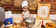 Enki joined the competition — help win amazing prizes! apron, baby, baking, baking_supplies, bread, brick_wall, chef_hat, child, cooking, croissants, cutting_board, floor, flour, food, homemade, kitchen, mixing_bowl, muffins, whisk, wooden_board
