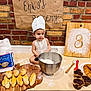 Enki joined the competition — help win amazing prizes! child, baby, chef_hat, apron, flour, mixing_bowl, whisk, bread, muffins, croissants, cutting_board, wooden_board, brick_wall, kitchen, baking, floor, homemade, food, cooking, baking_supplies