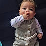 baby, belt, buttoned_outfit, child, clothing, comfortable, couch, curly_hair, cute, eyes, face, fingers, hand, indoor, infant, playful, portrait, sitting, skin, striped_shirt