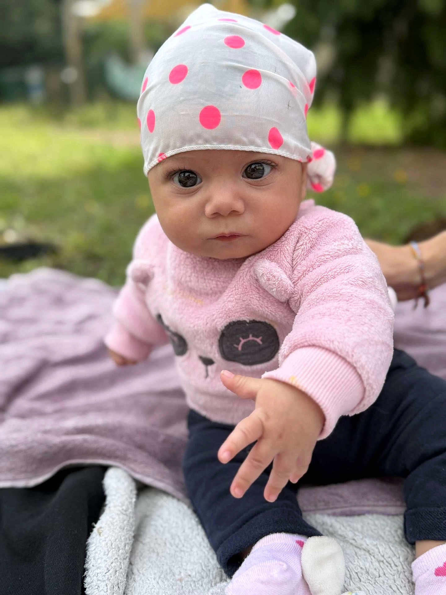 Ayna a rejoint le concours — aidez-le/la à gagner de superbes lots ! baby, child, infant, outdoor, grass, blanket, cap, polka_dots, pink_sweater, panda_face, socks, curious, young_child, cute, portrait, person, hand, sitting, nature, soft_clothing