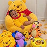baby, child, infant, portrait, sitting, winnie_the_pooh, stuffed_animal, tigger, eeyore, yellow, red, bee, honey, birthday_cake, birthday, nursery, carpet, indoor, smiling, toys
