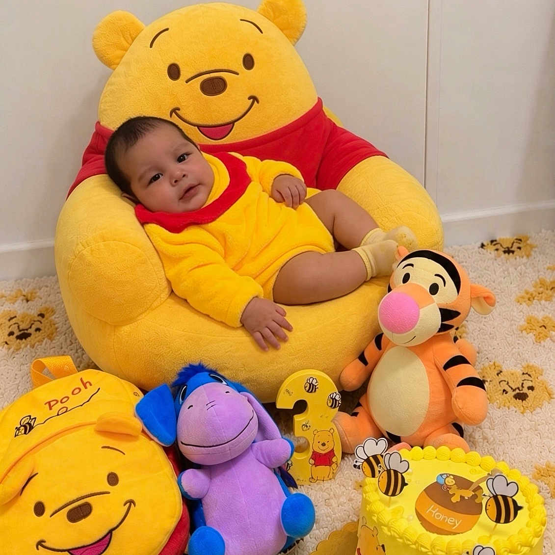 Jaryel Andrés is registered to the contest to win money with this photo: baby, child, infant, portrait, sitting, winnie_the_pooh, stuffed_animal, tigger, eeyore, yellow, red, bee, honey, birthday_cake, birthday, nursery, carpet, indoor, smiling, toys