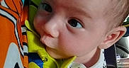 Emily is registered to the contest to win money with this photo: baby, child, closeup, clothing, colorful, curious, cute, eyes, face, fish_pattern, grip, hand, indoor, infant, orange, person, playtime, spot_pattern, toy, young