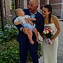 Caden is registered to the contest to win money with this photo: baby, man, woman, suit, dress, bouquet, flowers, outdoor, smile, happy, family, child, holding, greenery, building, stairs, pavement, plant, portrait, casual