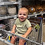 Caden joined the competition — help win amazing prizes! toddler, shopping_cart, store_aisle, home_decor, plant, pottery, brown_blanket, child, smiling, clothing, toy, metal_cart, retail, indoor, cute, person, baby, shopping, happy, face