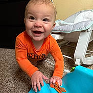 Caden joined the competition — help win amazing prizes! baby, child, smiling, crawling, orange_clothing, blue_toy, carpet, indoor, baby_rocker, happy, face, hands, furniture, playtime, infant, cute, person, home, toddler, floor
