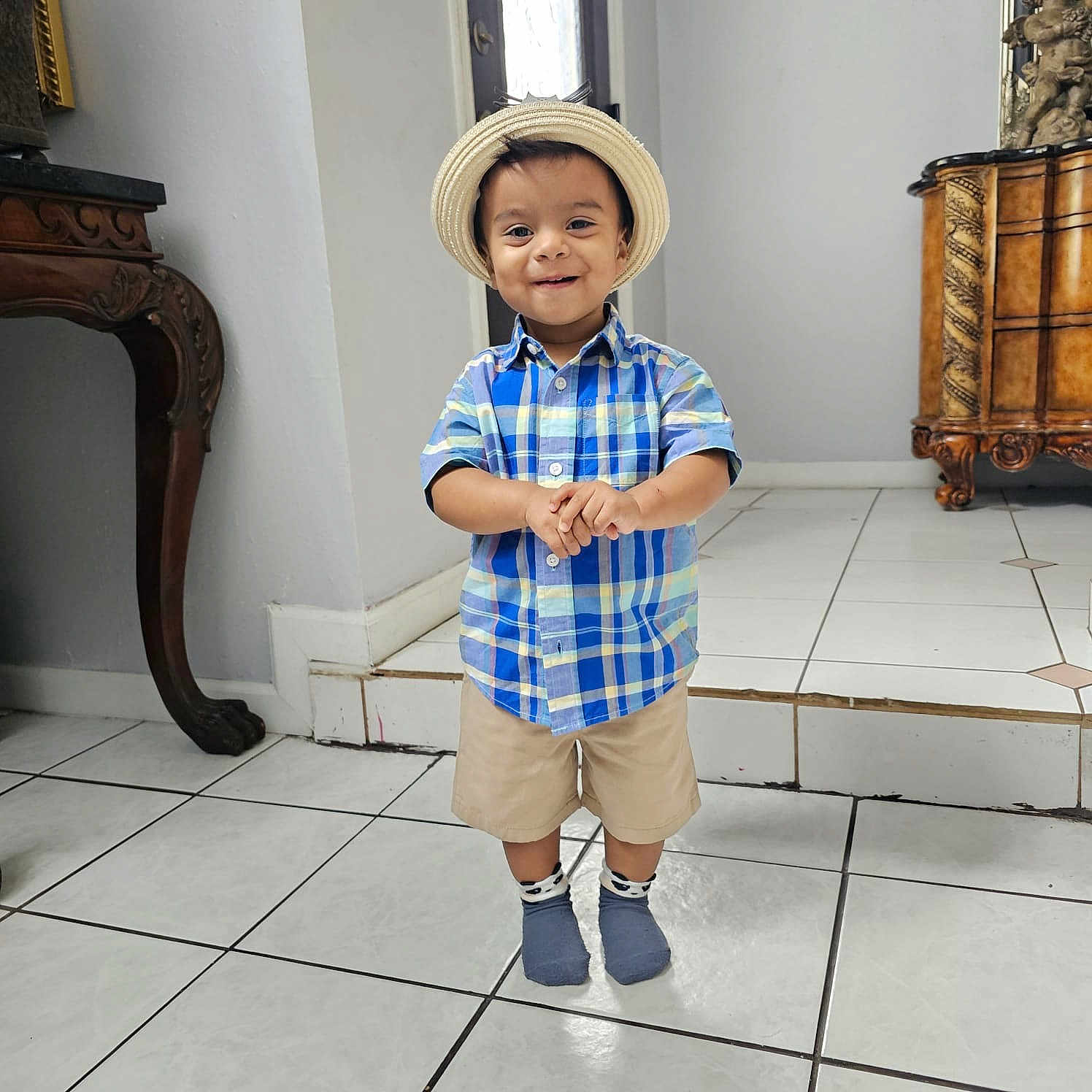 Ezra joined the competition — help win amazing prizes! toddler, child, indoor, hat, plaid_shirt, shorts, socks, smiling, standing, floor_tiles, furniture, vintage, wall, door, person, happy, portrait, cute, home, clothing