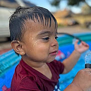 Ezra joined the competition — help win amazing prizes! toddler, child, wet_hair, water_droplets, inflatable_pool, maroon_shirt, playing, outdoor, summer, water, hose, closeup, portrait, young_child, fun, daytime, skin, face, expression, background_blur
