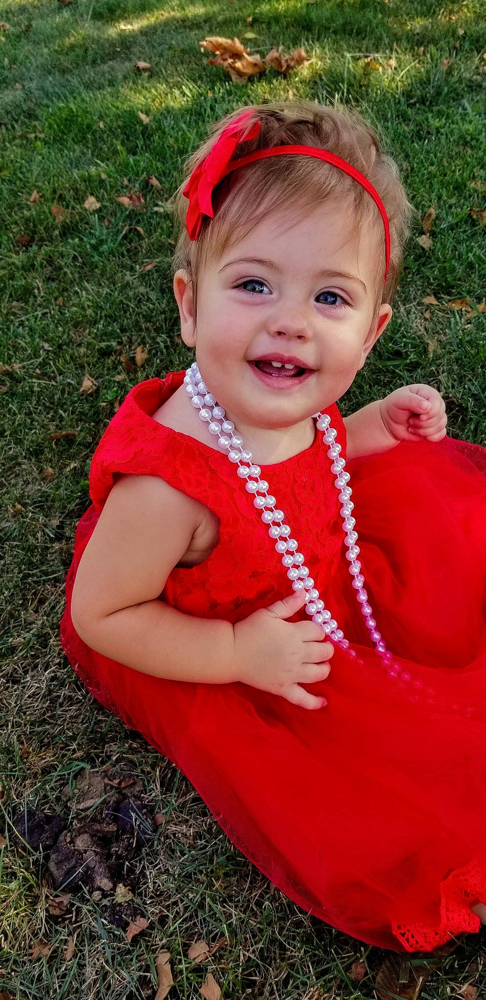 Rosalyn is registered to the contest to win money with this photo: baby, child, child_model, clothing, costume, fashion_accessory, grass, hair_accessory, headband, headgear, headwear, joy, outerwear, pattern, person, red, smile, toddler