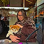 Charly participe au concours pour gagner de l'argent avec cette photo : woman, puppy, dog, glasses, scarf, leopard_print, coat, cafe, table, fairy_lights, glass_window, hand, purse, warm_lighting, reflection, indoor, seated, cute, pet, cozy