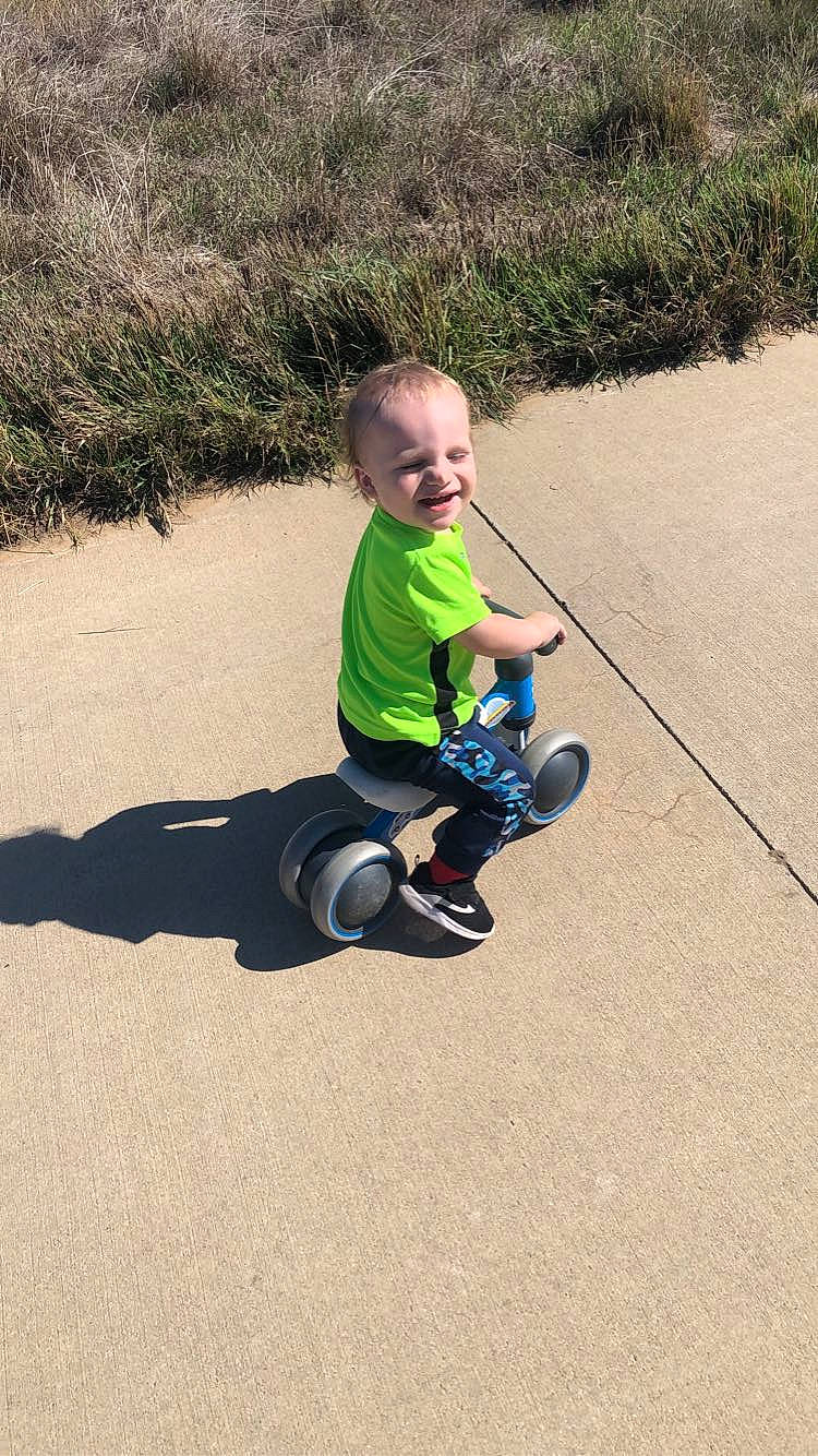 Easton is registered to the contest to win money with this photo: asphalt, baby, baby_toddler_clothing, fun, grass, happy, knee, landscape, leisure, people_in_nature, person, plant, recreation, shadow, sitting, smile, soil, t_shirt, toddler, toy