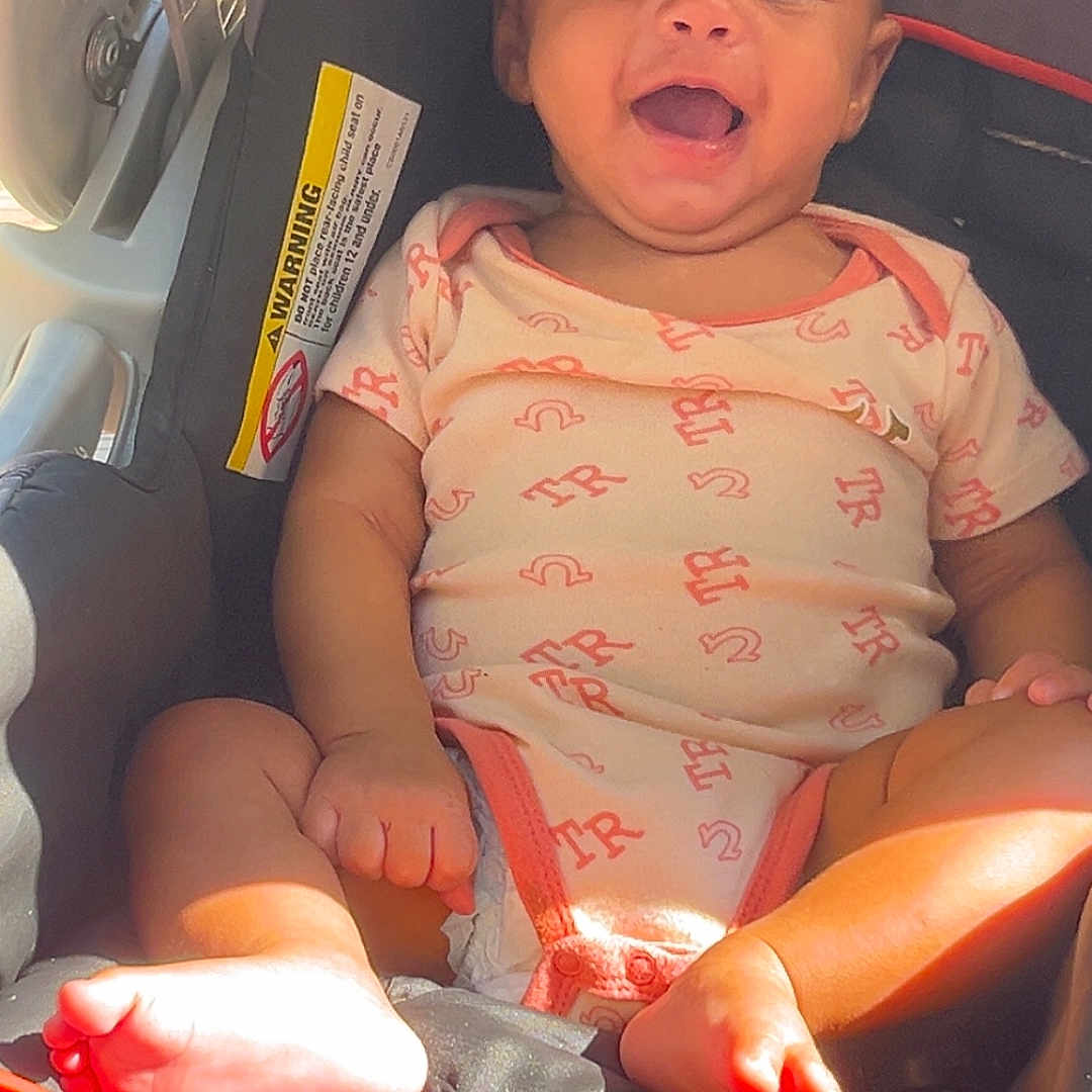 Miaya is registered to the contest to win money with this photo: baby, baby_girl, car_safety, car_seat, child, clothing, cute, foot, happy, indoors, infant, infant_clothing, person, portrait, seatbelt, sitting, smiling, sunlight, toes, young_child