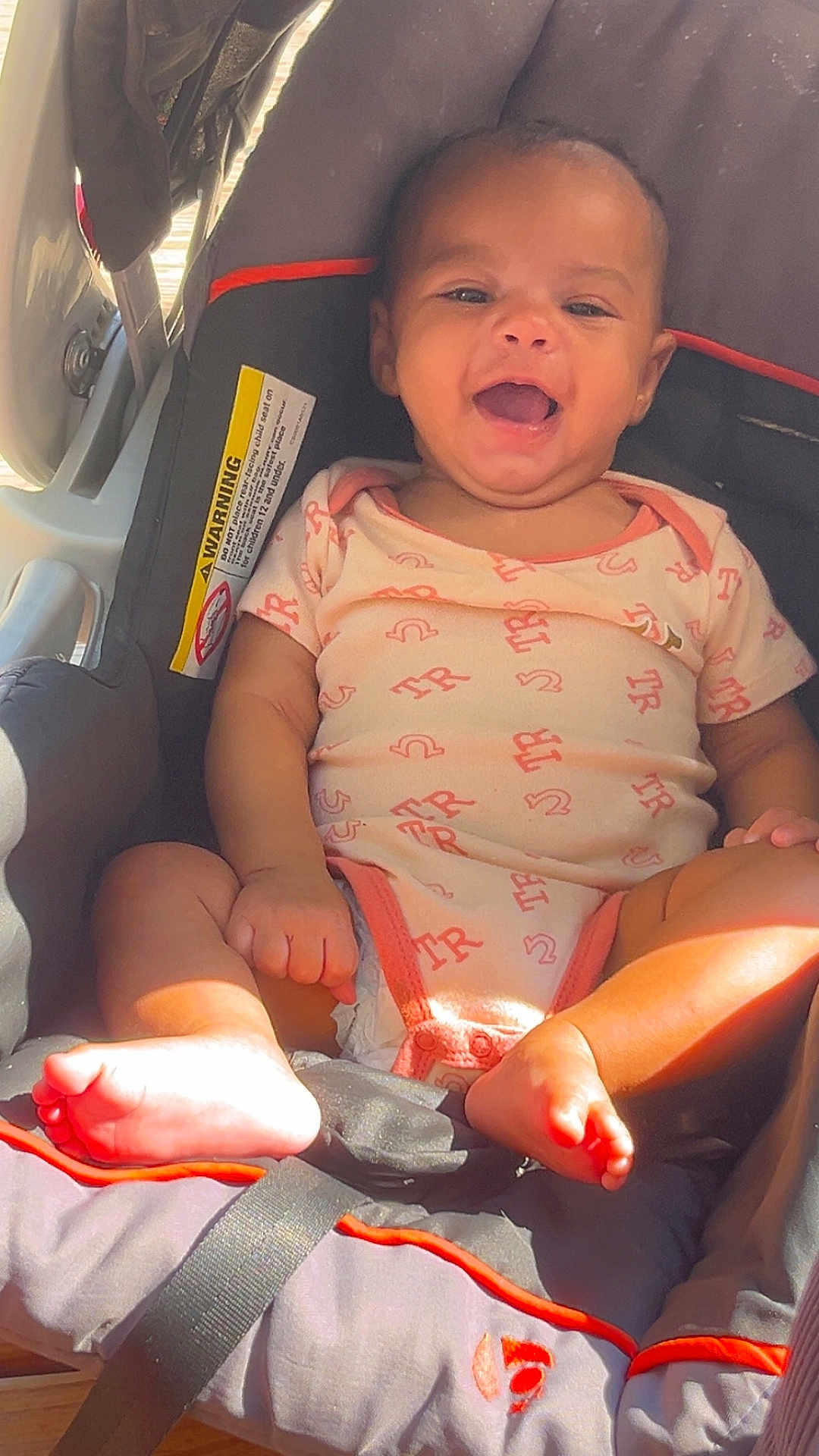 Miaya is registered to the contest to win money with this photo: baby, infant, car_seat, smiling, happy, child, cute, foot, toes, clothing, seatbelt, indoors, sunlight, person, portrait, sitting, baby_girl, infant_clothing, car_safety, young_child