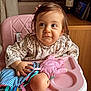 bottle, child, clothing, curious, doll, expression, face, floor, furniture, hair, high_chair, home, indoor, living_room, person, pink, sitting, table, toddler, toy