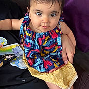 Melody is registered to the contest to win money with this photo: baby, toddler, child, person, face, eyes, dress, colorful_clothing, sitting, arm, hand, foot, indoor, couch, adult, holding, purple_background, black_clothing, cute, portrait