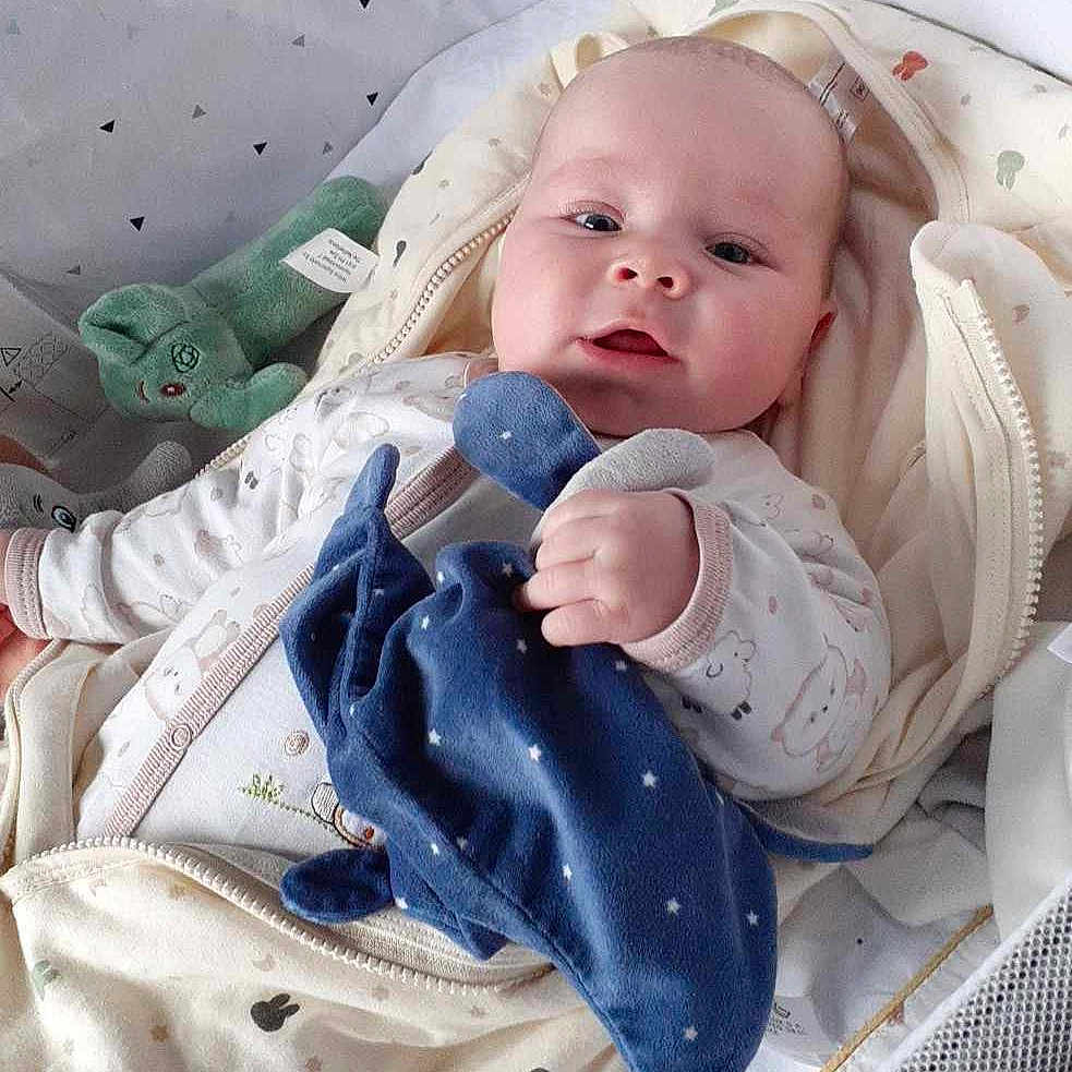 Emilio Kalavassis a rejoint le concours — aidez-le/la à gagner de superbes lots ! baby, baby_clothing, baby_face, child, comfort, crib, cute, fabric, hand, indoors, infant, lying_down, mesh, newborn, patterned_bedding, plush_toy, resting, sleeping_bag, sleepwear, soft_toys