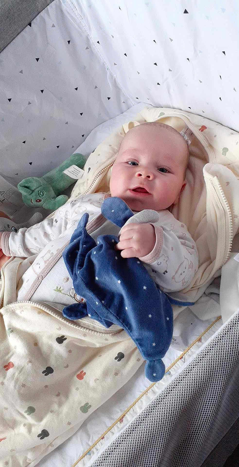 Emilio Kalavassis a rejoint le concours — aidez-le/la à gagner de superbes lots ! baby, baby_clothing, baby_face, child, comfort, crib, cute, fabric, hand, indoors, infant, lying_down, mesh, newborn, patterned_bedding, plush_toy, resting, sleeping_bag, sleepwear, soft_toys