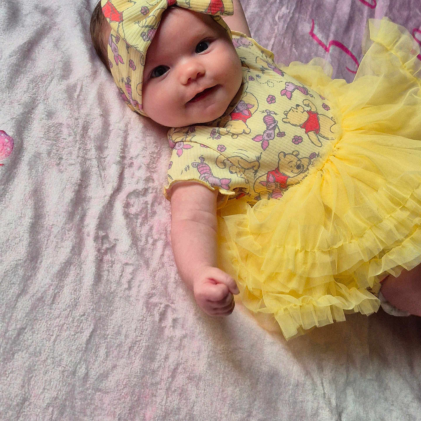 Tinley joined the competition — help win amazing prizes! baby, blanket, child, clothing, cute, cute_outfit, face, happy, headband, indoors, infant, lying_down, portrait, skin, smiling, soft_texture, toddler, tutu, winnie_the_pooh, yellow_dress
