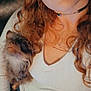 woman, dog, curly_hair, nose_ring, choker, white_top, small_dog, pet, indoor, selfie, casual, relaxed, couch, hand, fur, looking_up, portrait, closeup, human, animal