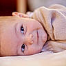 baby, infant, face, eyes, smile, sweater, lying_down, closeup, portrait, skin, head, cute, warm_clothing, indoors, soft_light, expression, newborn, child, peaceful, resting