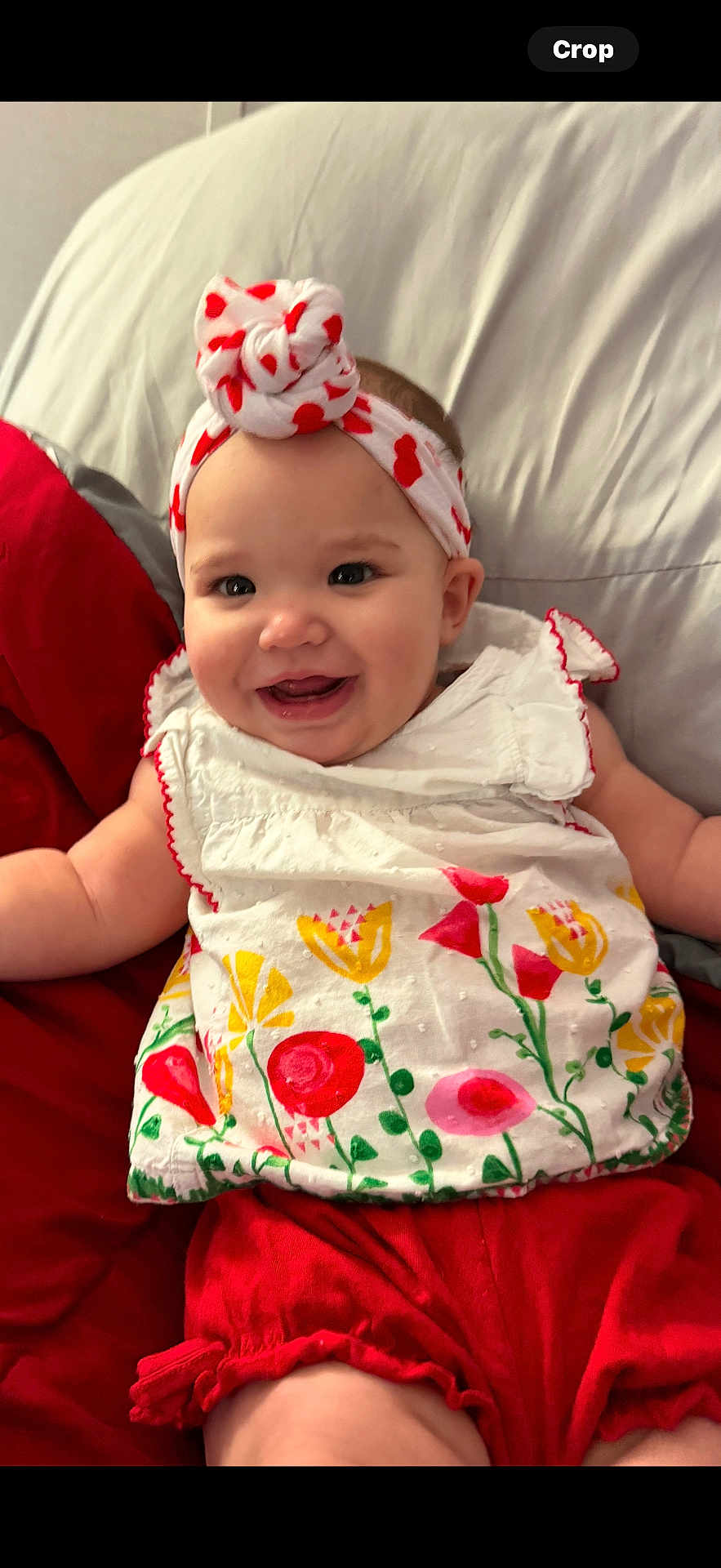 Journei joined the competition — help win amazing prizes! baby, child, smiling, headband, dress, floral_pattern, red, white, pillow, bed, indoor, cute, happy, person, infant, clothing, sitting, face, portrait, young_child