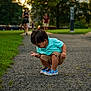 Malachi joined the competition — help win amazing prizes! child, boy, curious, squatting, polo_shirt, shorts, colorful_shoes, pathway, park, greenery, trees, people, outdoor, daylight, focus, blurred_background, nature, summer, casual_clothing, exploration