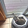 cat, gray_cat, pet_bed, quilted_bed, pink_collar, tile_floor, sliding_door, screen_door, stretching, napping, indoor, natural_light, cozy, relaxed, feline, paw, sleeping, home, quiet, peaceful